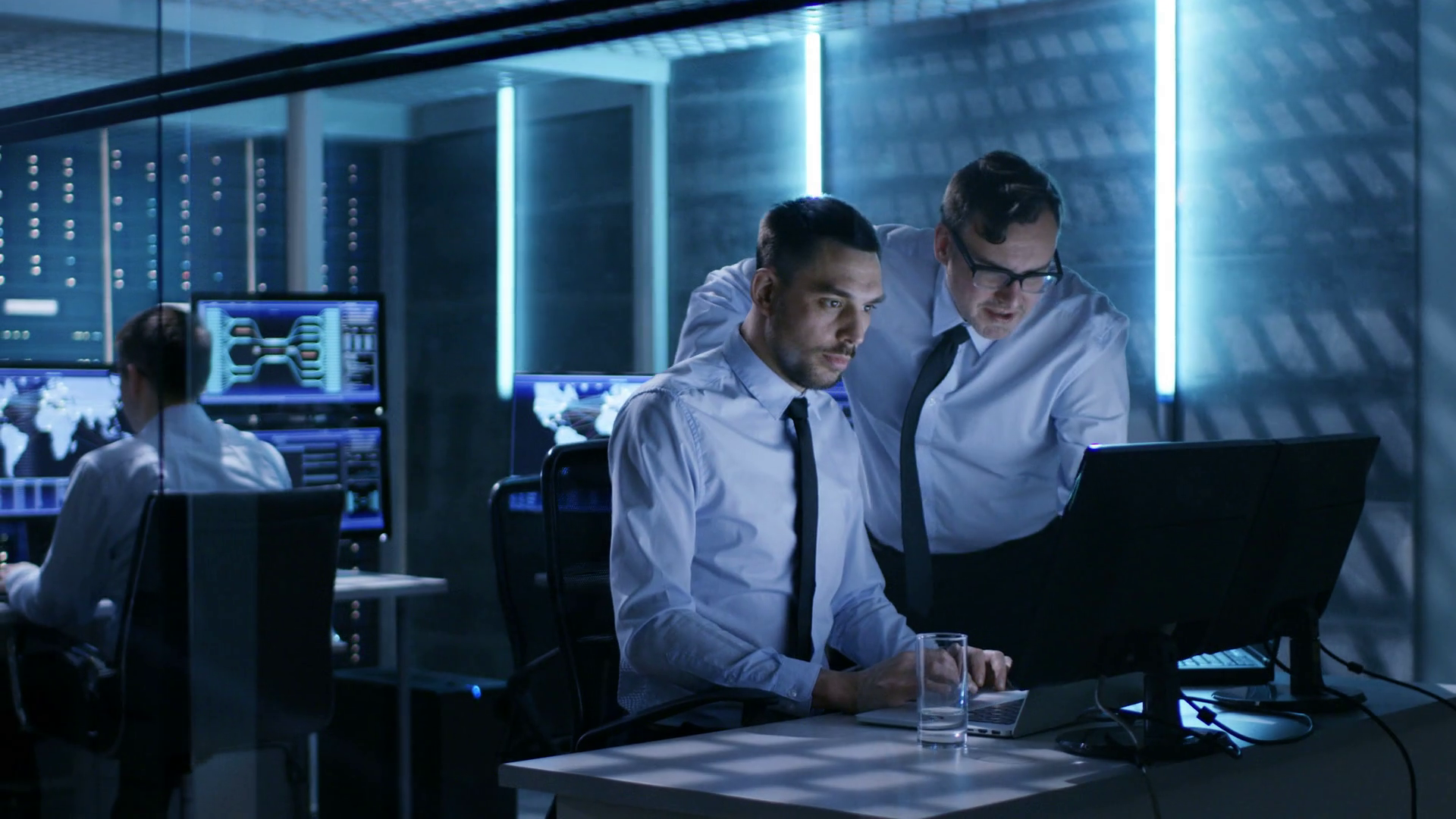 videoblocks-two-operation-engineers-working-on-solving-problems-in-system-control-room-in-the-background-their-colleague-displays-and-server-racks-shot-on-red-epic-w-8k-helium-cinema-camera_brxu9hj0x_thumbnail-full01.png